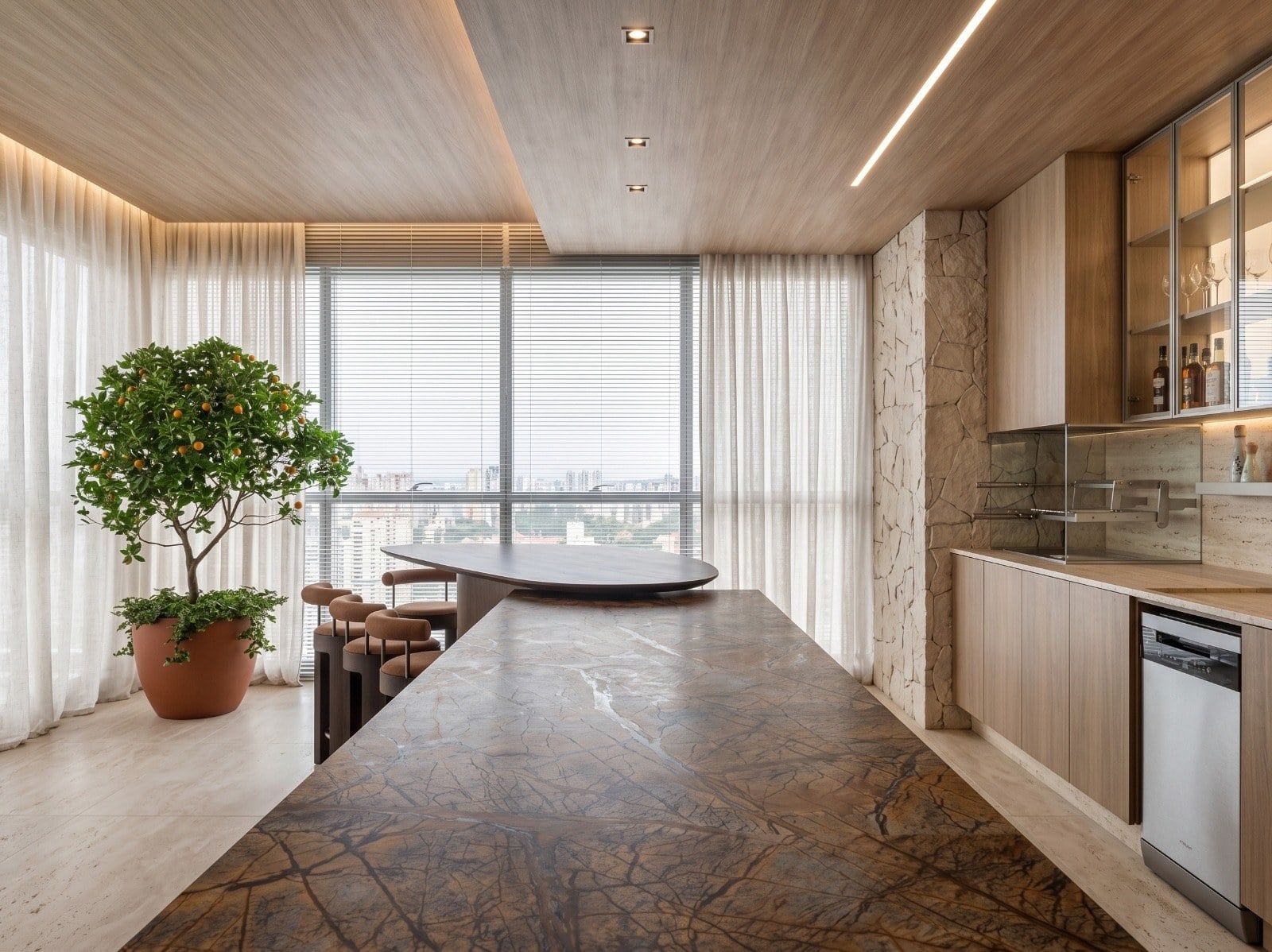 Cozinha gourmet com mesa longa de pedra natural, marcenaria clara, forro de madeira e uma árvore em vaso junto à janela